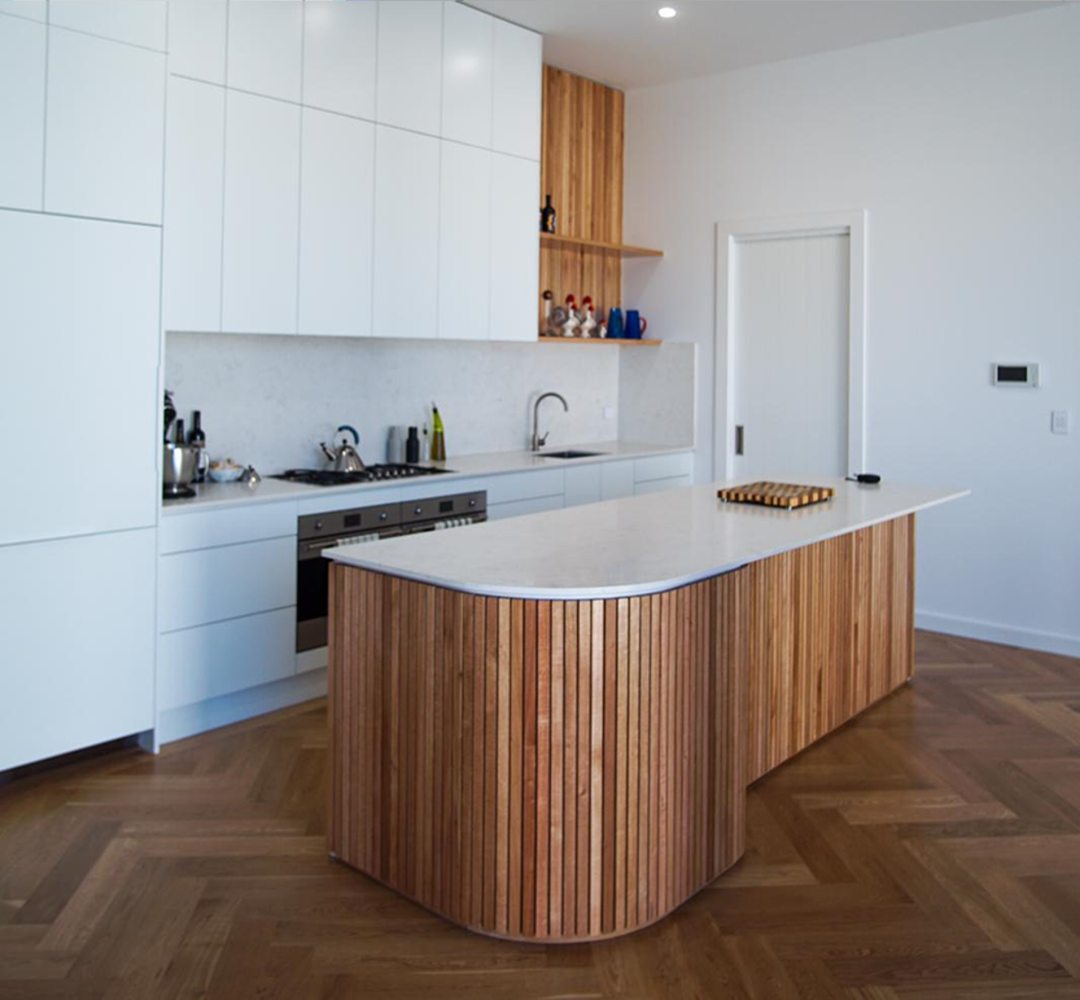 Contemporary kitchen with curved timber slatted island and herringbone floors
